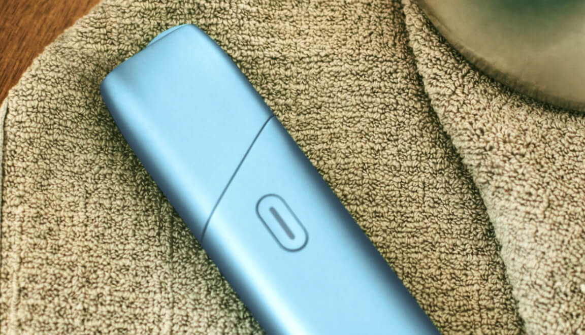 IQOS Originals ONE Heated tobacco device in turquoise color on a table cloth.