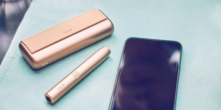 IQOS ILUMA PRIME držač i džepni punjač pokraj mobitela.