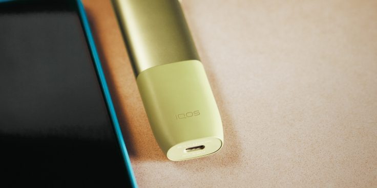 IQOS ILUMA ONE poleg mobitela.