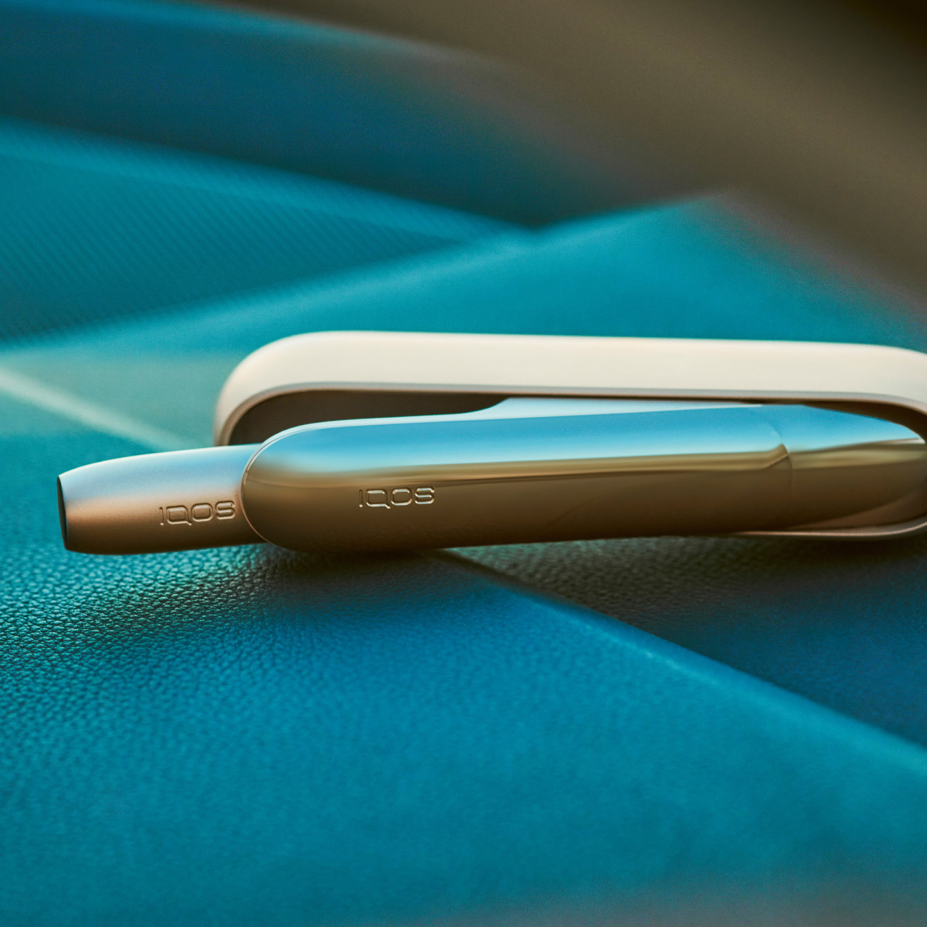 IQOS device and its charger on a blue background
