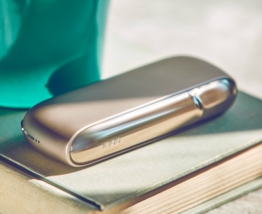 Brilliant gold IQOS 3 DUO on a book against a green background